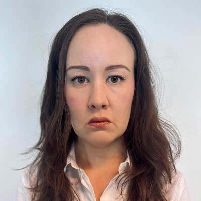 Simonette has brown shoulder length hair and wearing a white shirt