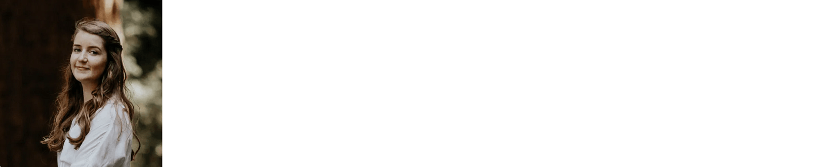 Karla has long brown hair and is wearing white, smiling in the outdoors